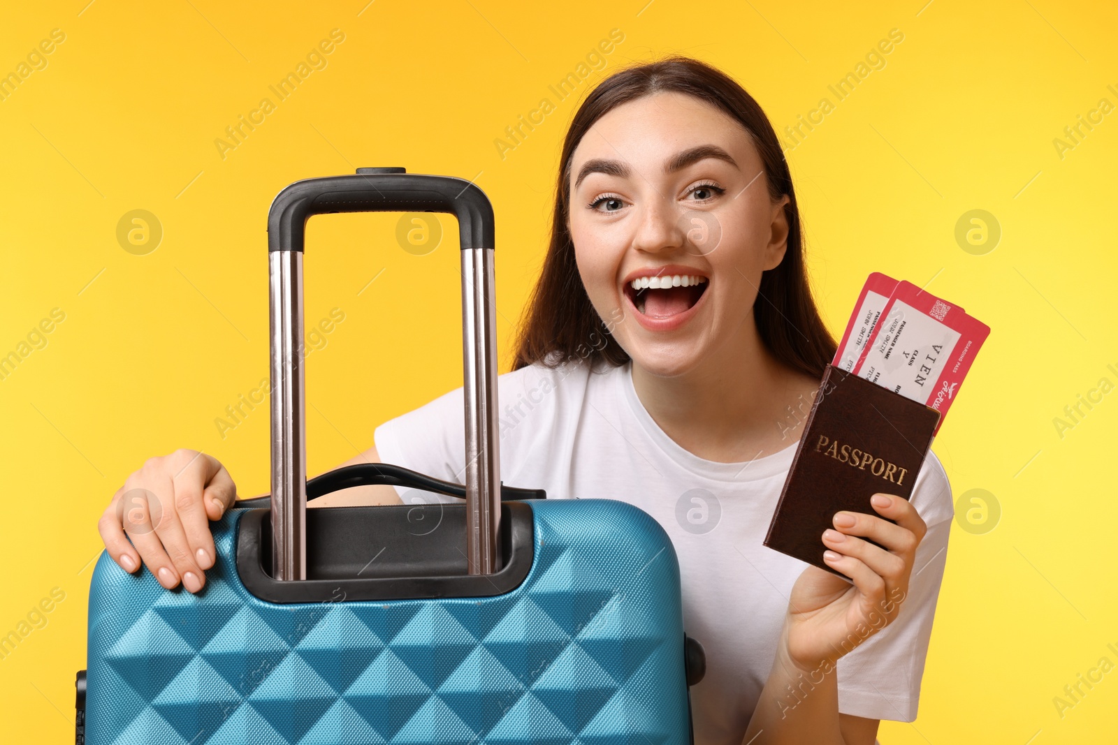 Photo of Woman with tickets, passport and suitcase on orange background