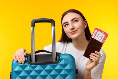 Photo of Woman with tickets, passport and suitcase on orange background