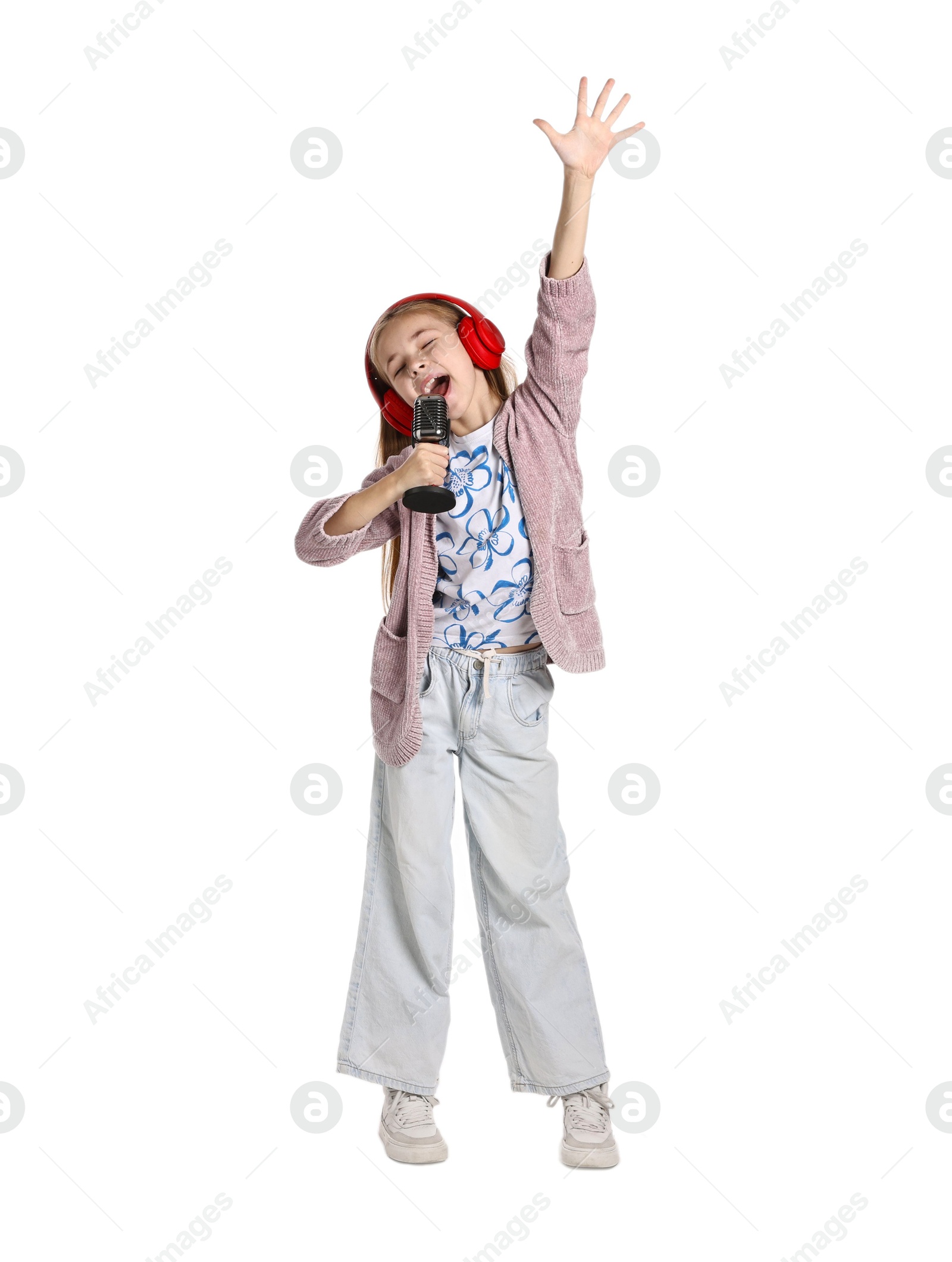 Photo of Little girl with microphone and headphones singing on white background