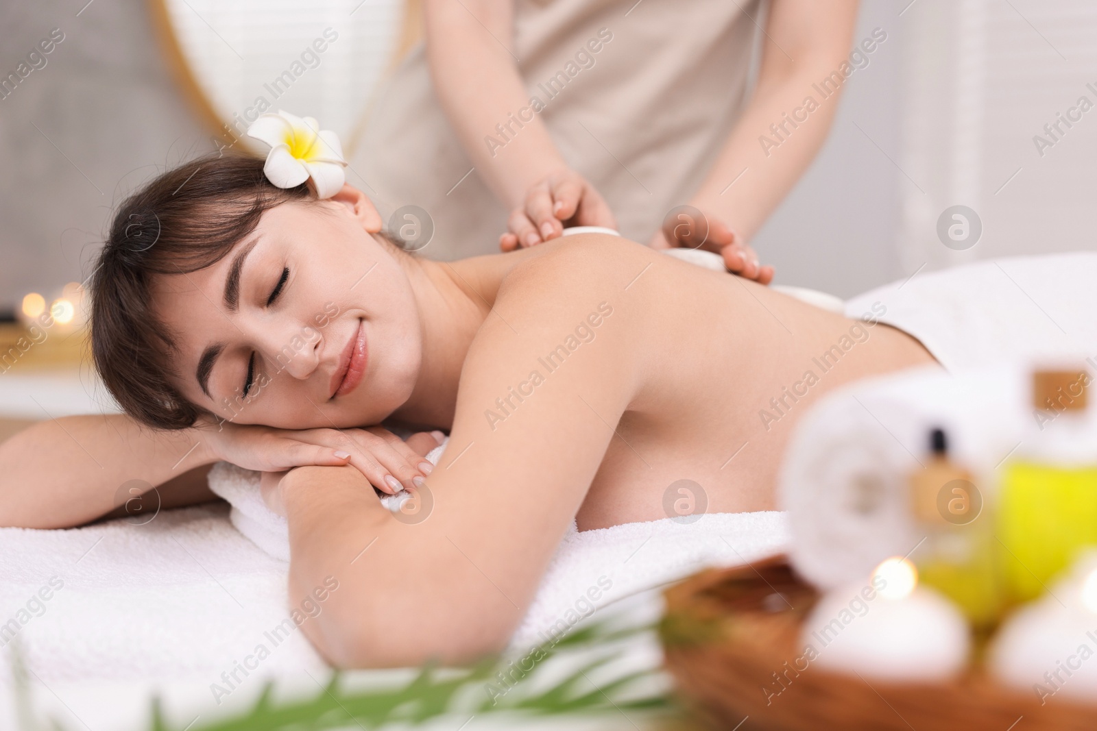 Photo of Young woman receiving hot stone massage in spa salon