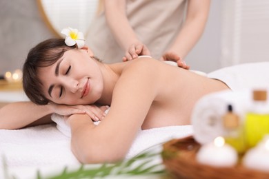 Young woman receiving hot stone massage in spa salon