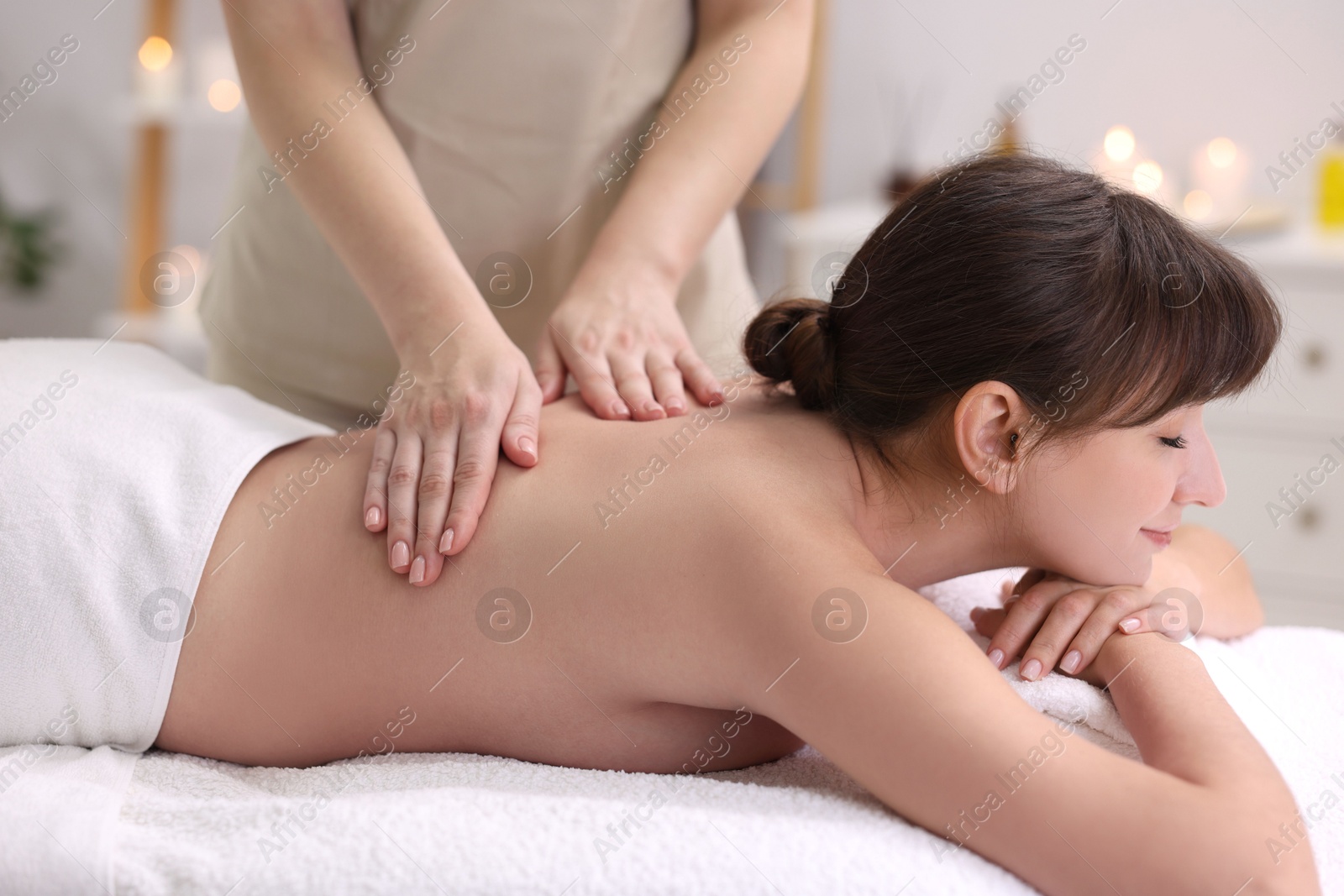 Photo of Young woman receiving back massage in spa salon