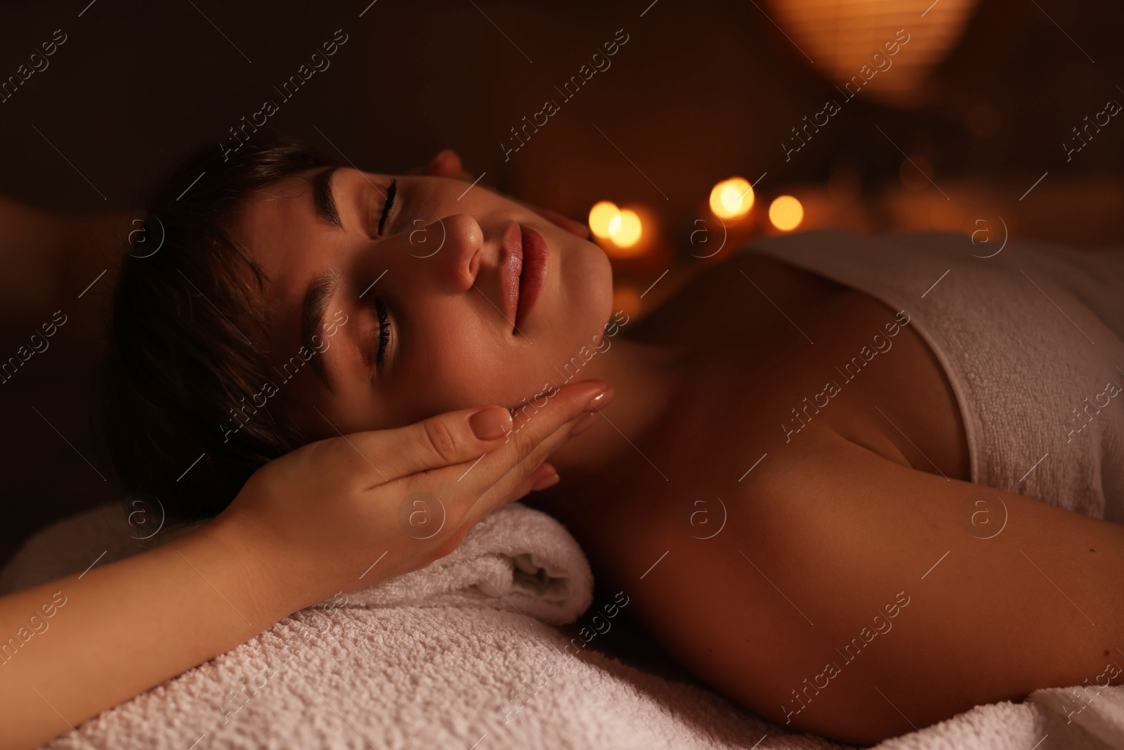 Photo of Young woman receiving face massage in spa salon