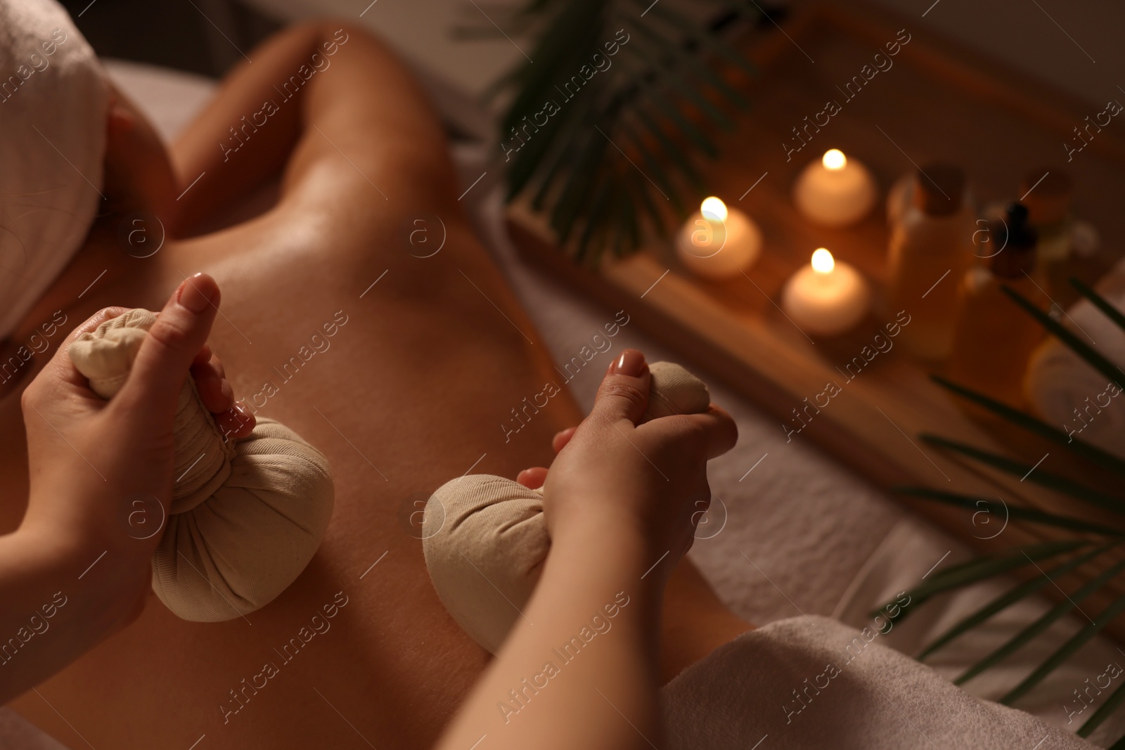 Photo of Woman receiving back massage with herbal bags in spa salon, closeup