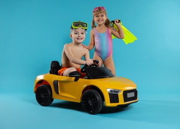 Photo of Cute little kids in beachwear with toy car on light blue background