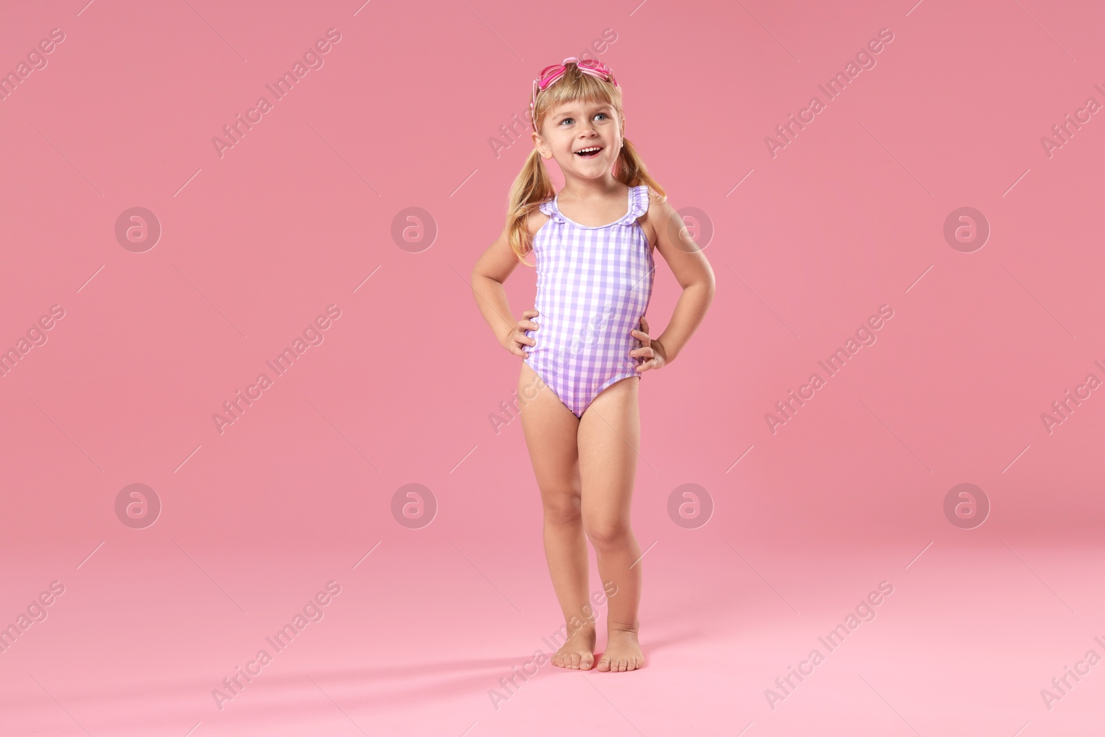 Photo of Cute little girl in beachwear with diving mask on pink background