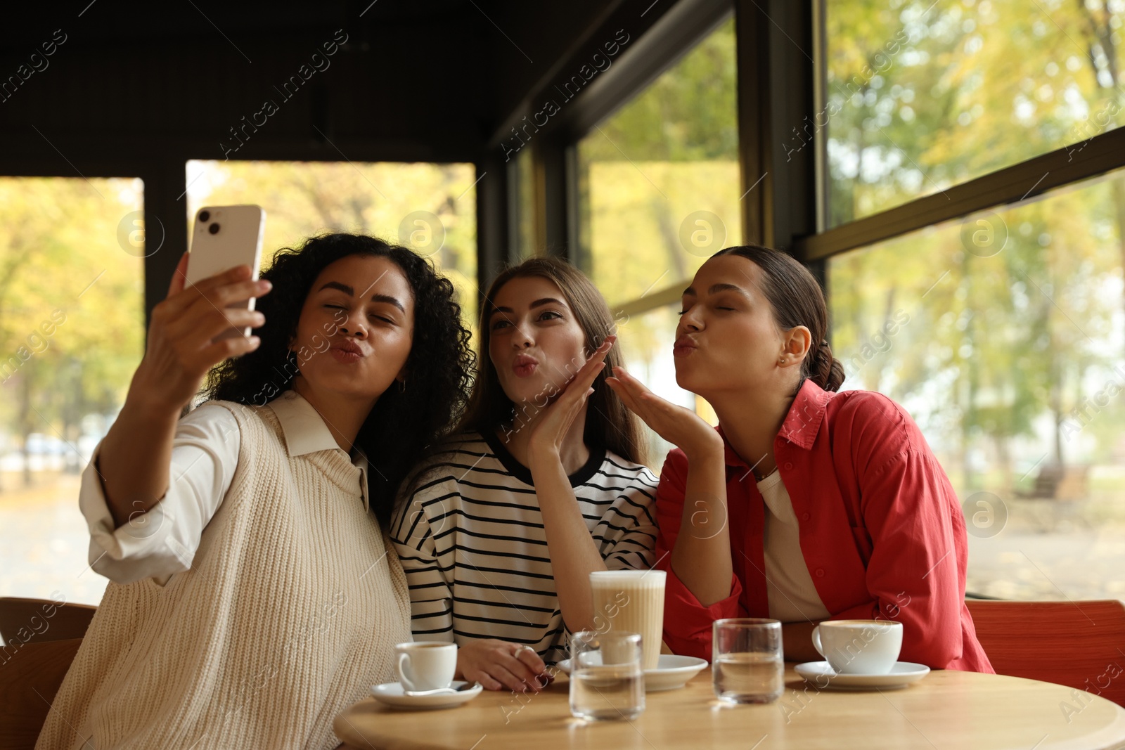 Photo of Happy friends taking selfie during coffee meeting in cafe