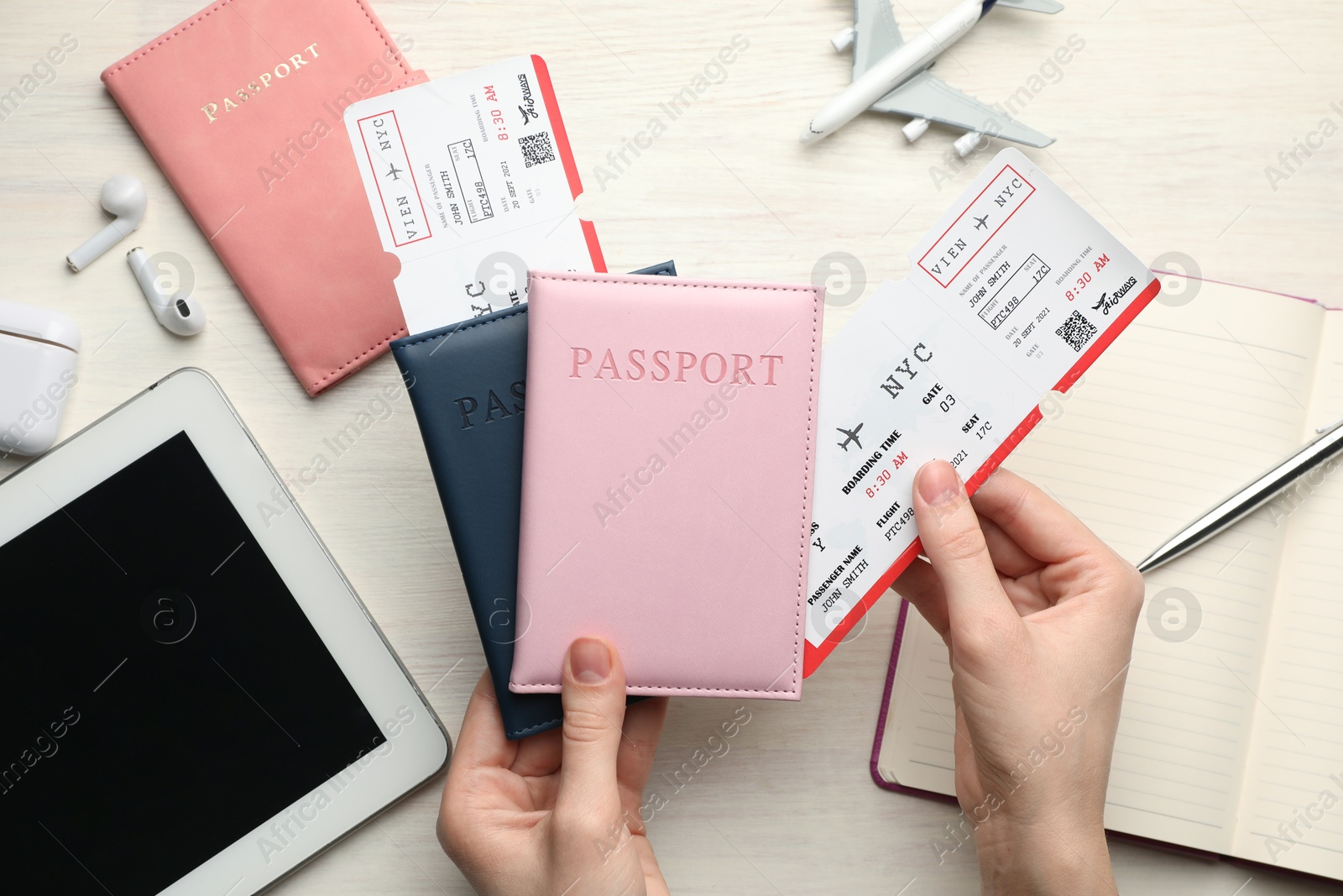 Photo of Travel agency. Woman with flight tickets and passports at light wooden table, top view