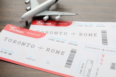 Photo of Travel agency. Flight tickets and plane model on wooden table, closeup