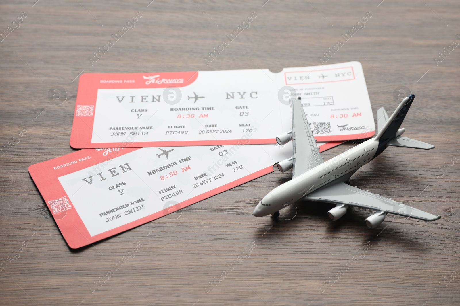 Photo of Travel agency. Flight tickets and plane model on wooden table, closeup