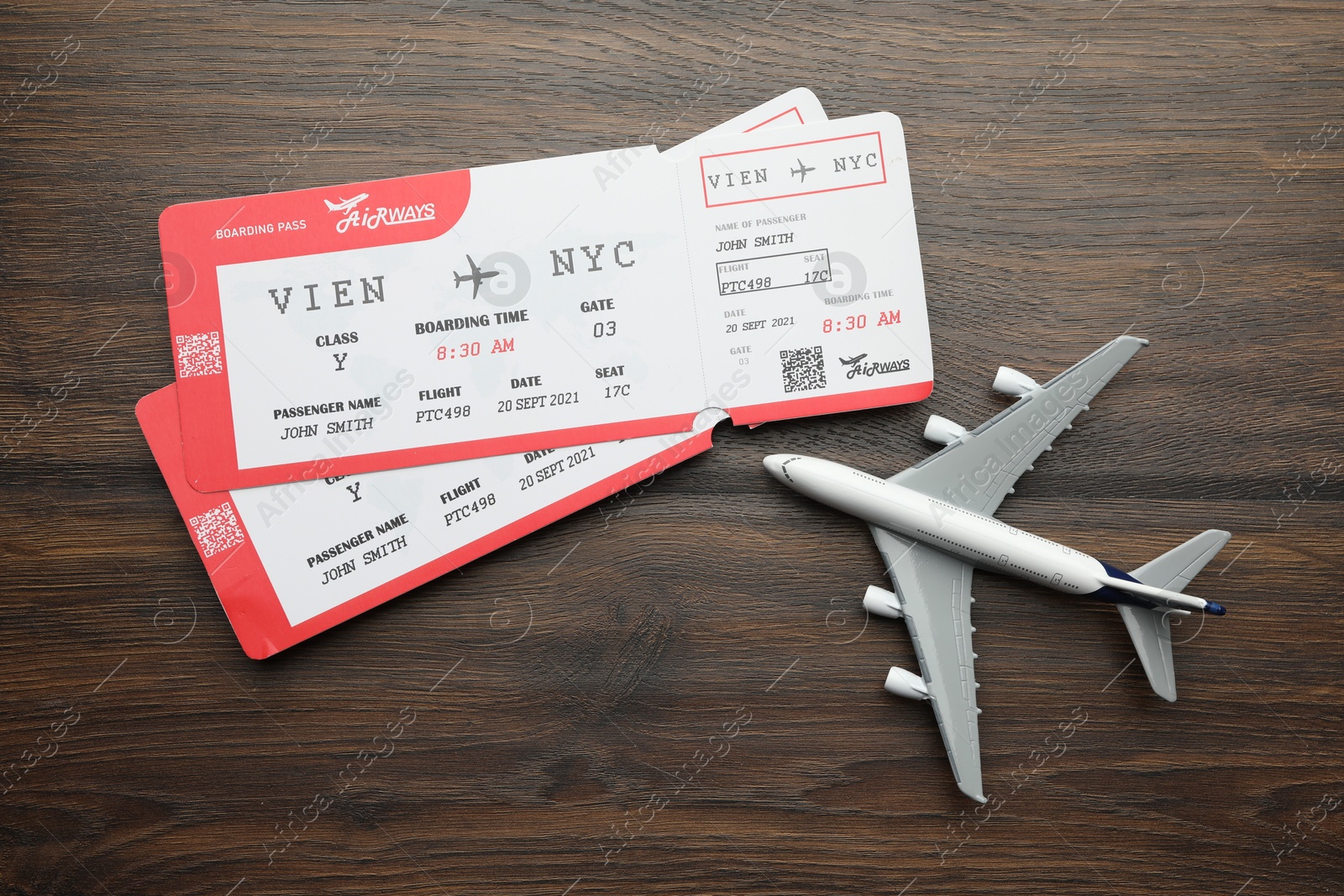 Photo of Travel agency. Flight tickets and plane model on wooden table, flat lay