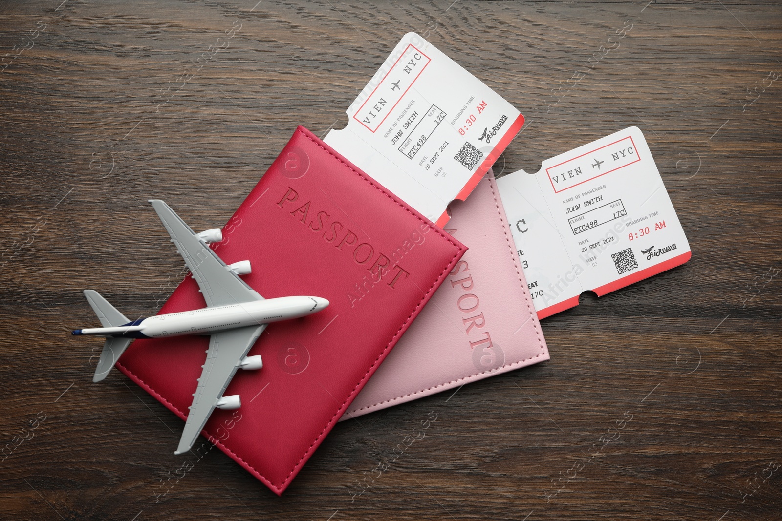 Photo of Travel agency. Flight tickets, passports and plane model on wooden table, flat lay