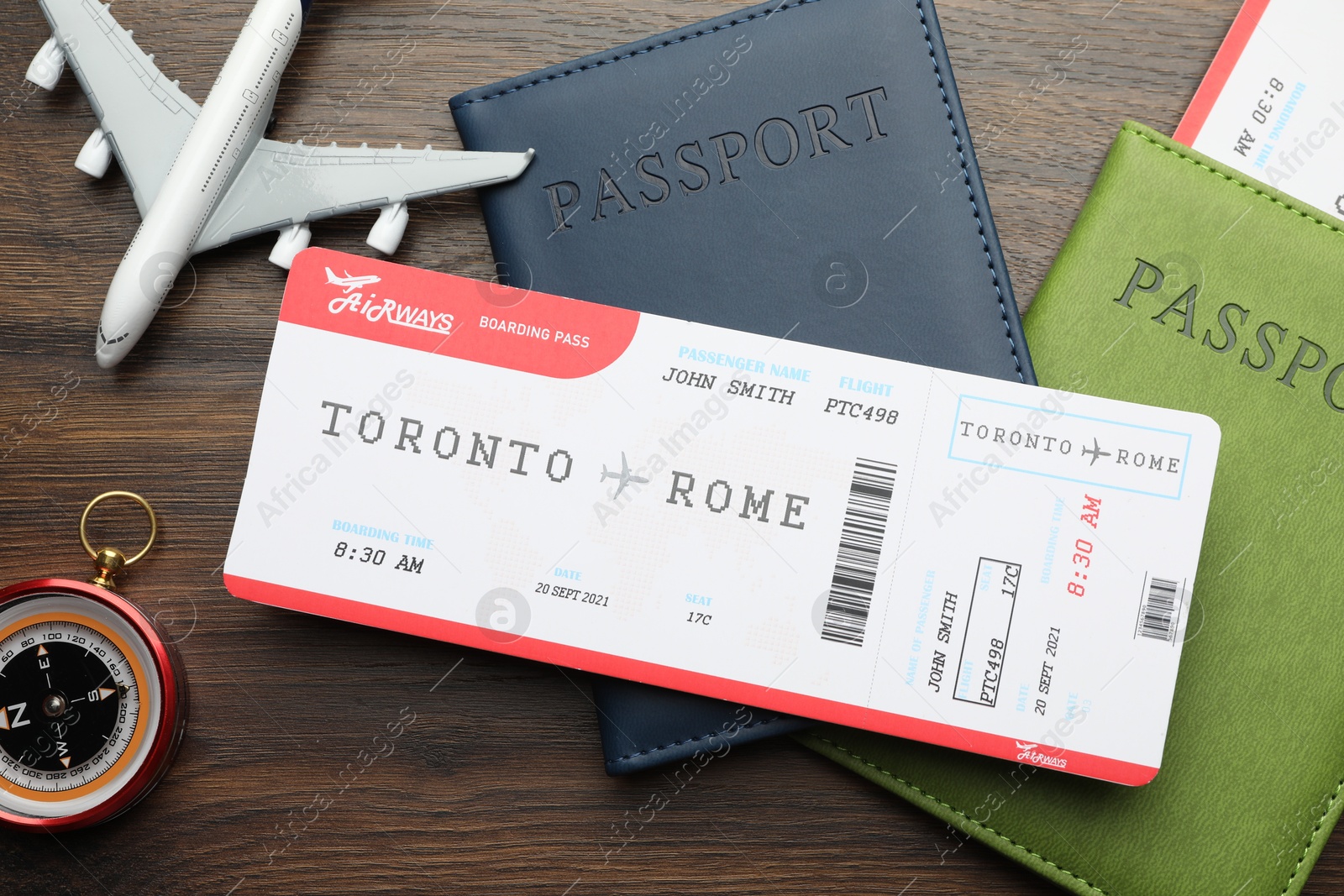 Photo of Travel agency. Flight tickets, passports, plane model and compass on wooden table, flat lay