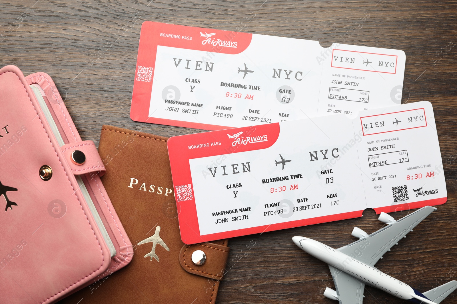 Photo of Travel agency. Flight tickets, passports and plane model on wooden table, flat lay