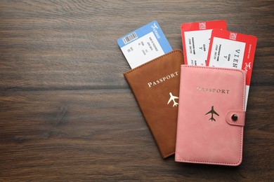 Photo of Travel agency. Flight tickets and passports on wooden table, flat lay. Space for text