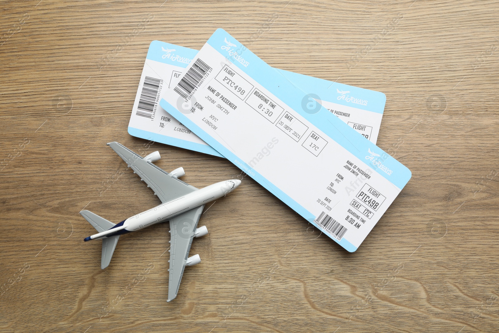 Photo of Travel agency. Flight tickets and plane model on wooden table, flat lay