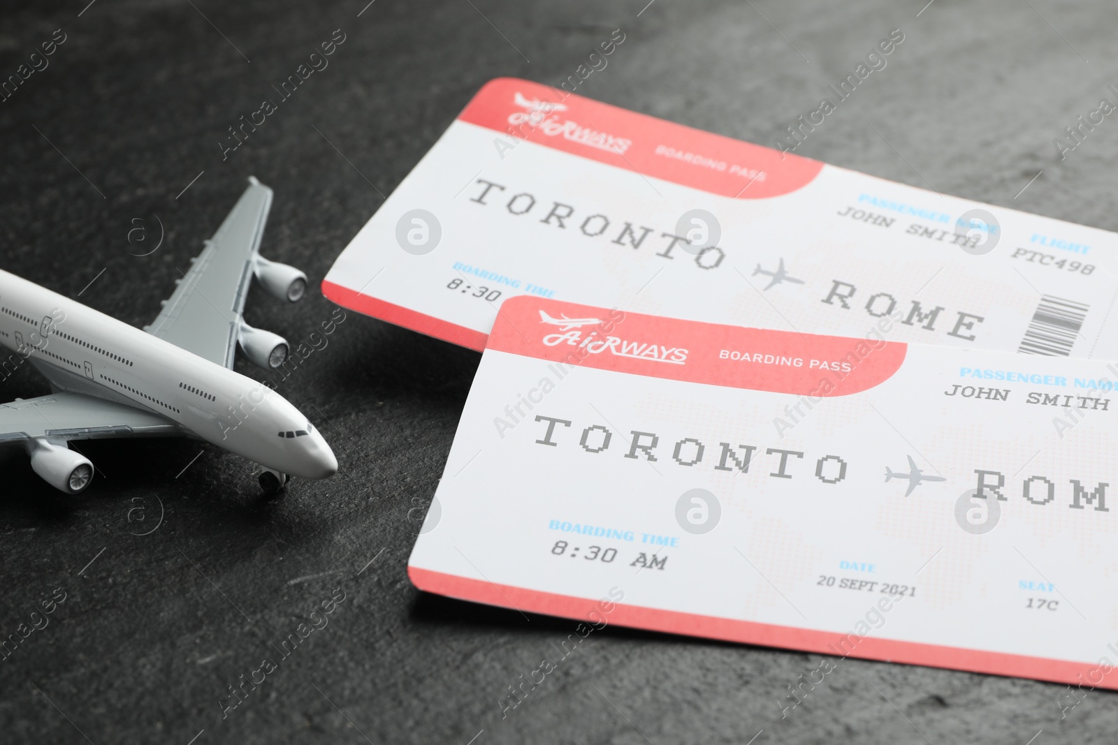 Photo of Travel agency. Flight tickets and plane model on dark textured table, closeup