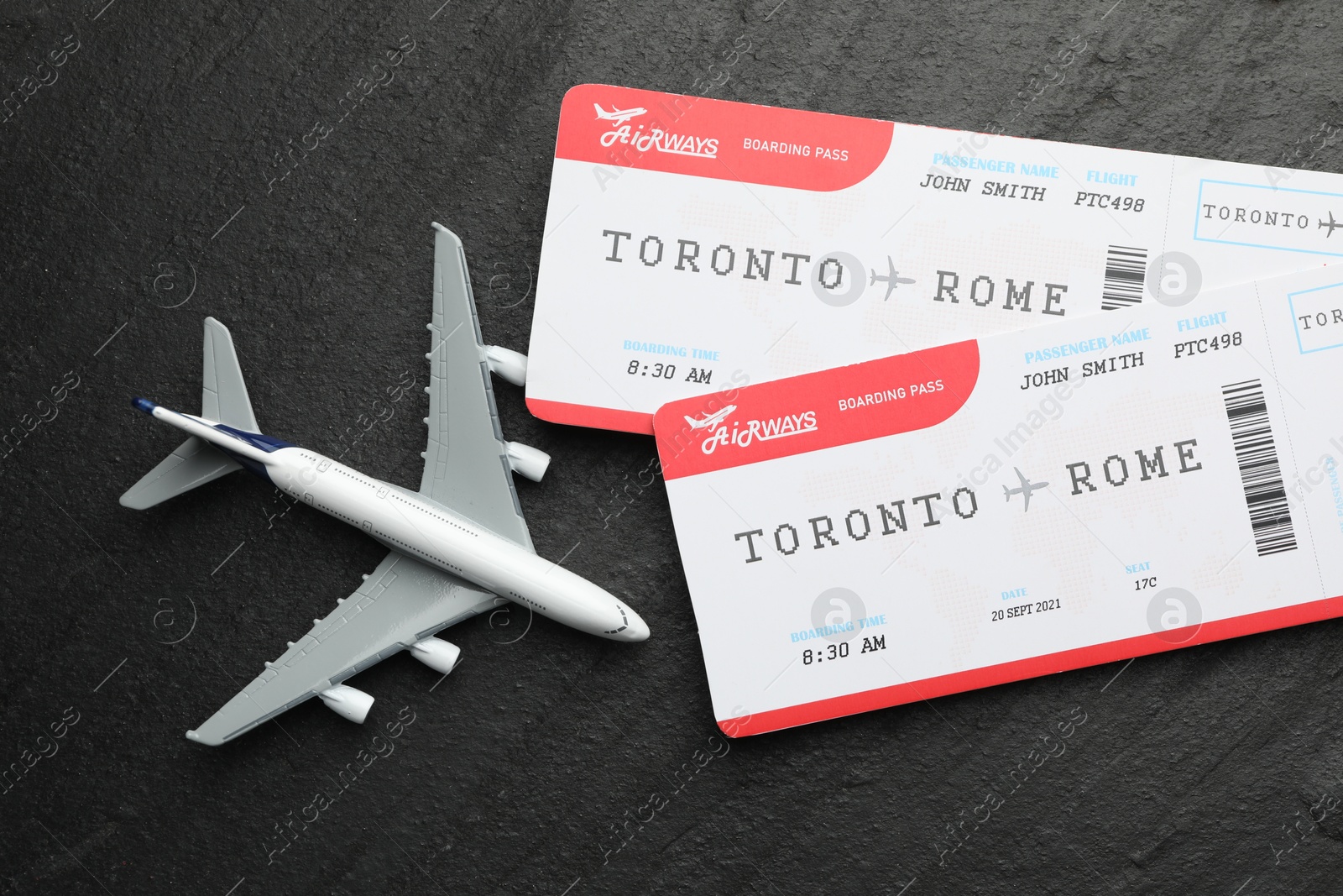 Photo of Travel agency. Flight tickets and plane model on dark textured table, flat lay