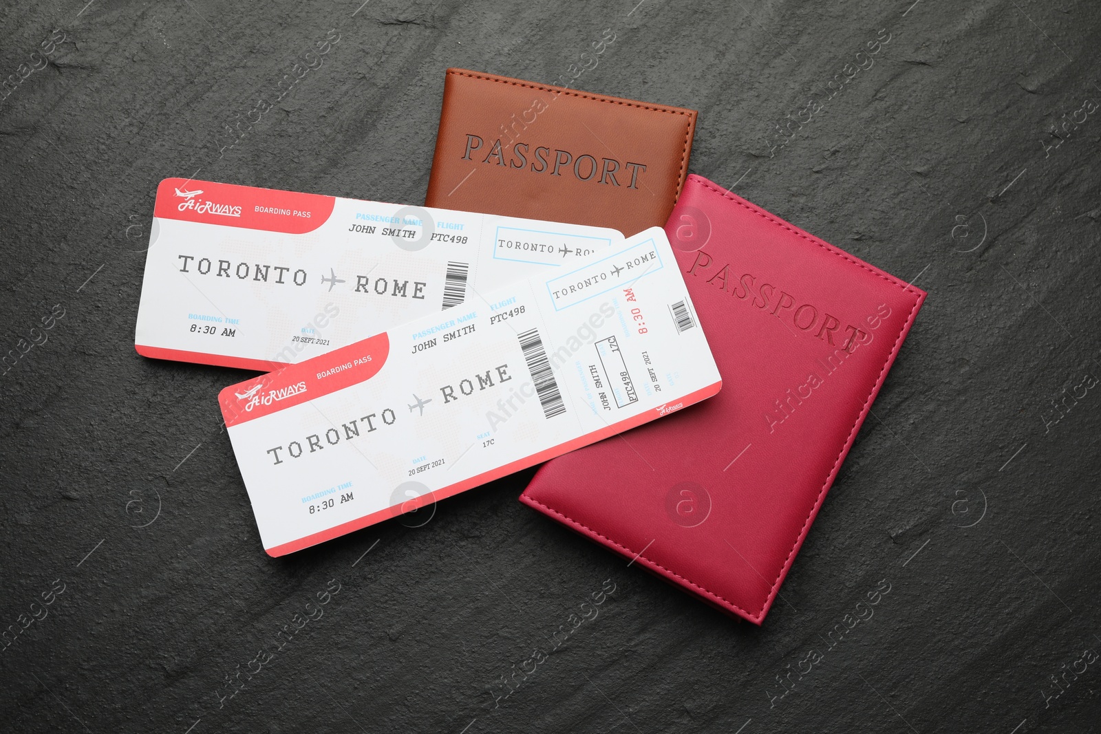 Photo of Travel agency. Flight tickets and passports on dark textured table, flat lay