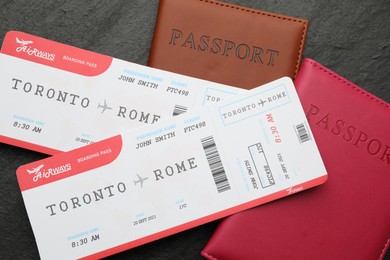 Photo of Travel agency. Flight tickets and passports on dark textured table, flat lay