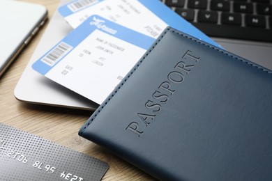 Photo of Travel agency. Flight tickets, passport, credit card and laptop on wooden table, closeup