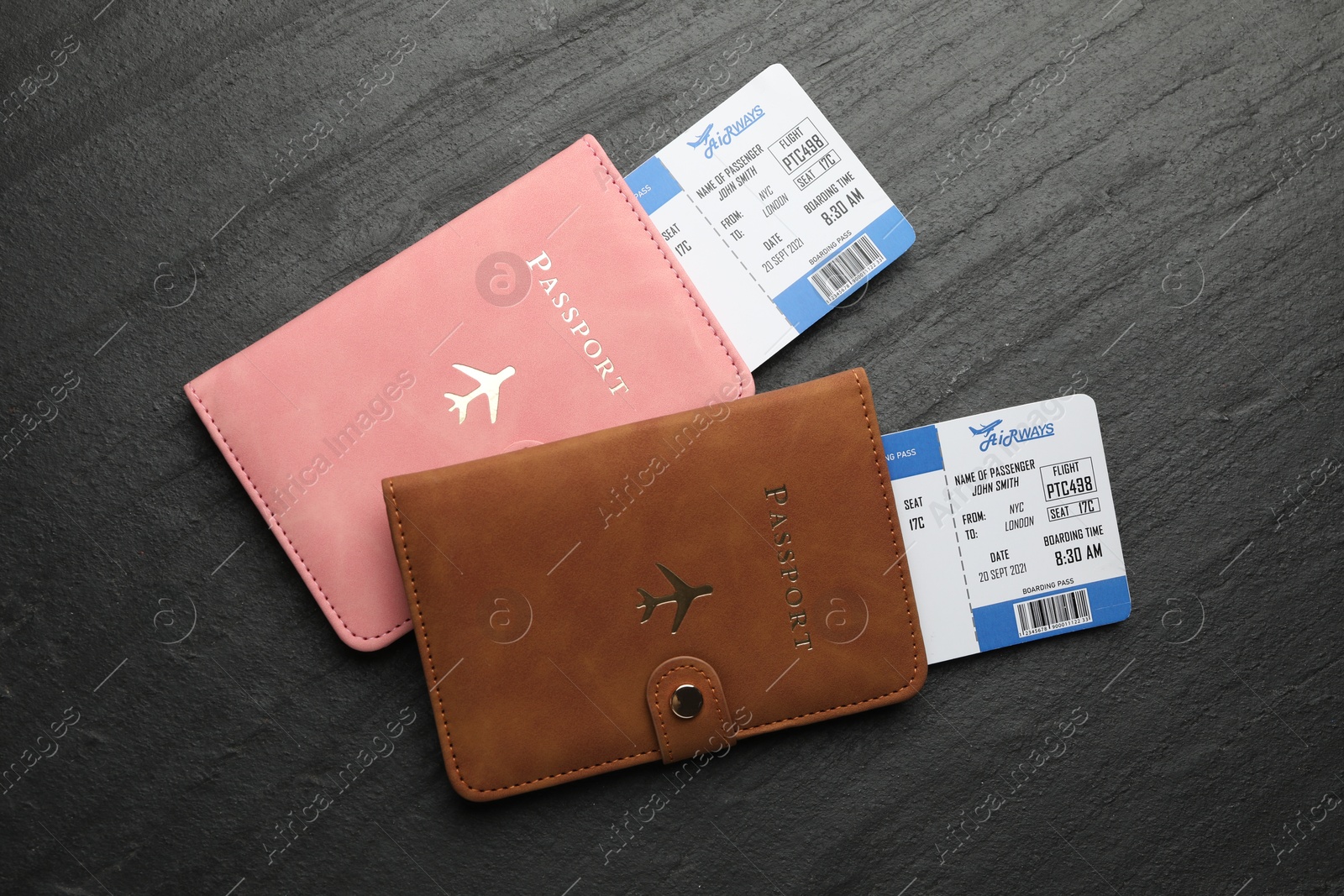 Photo of Travel agency. Flight tickets and passports on dark textured table, flat lay