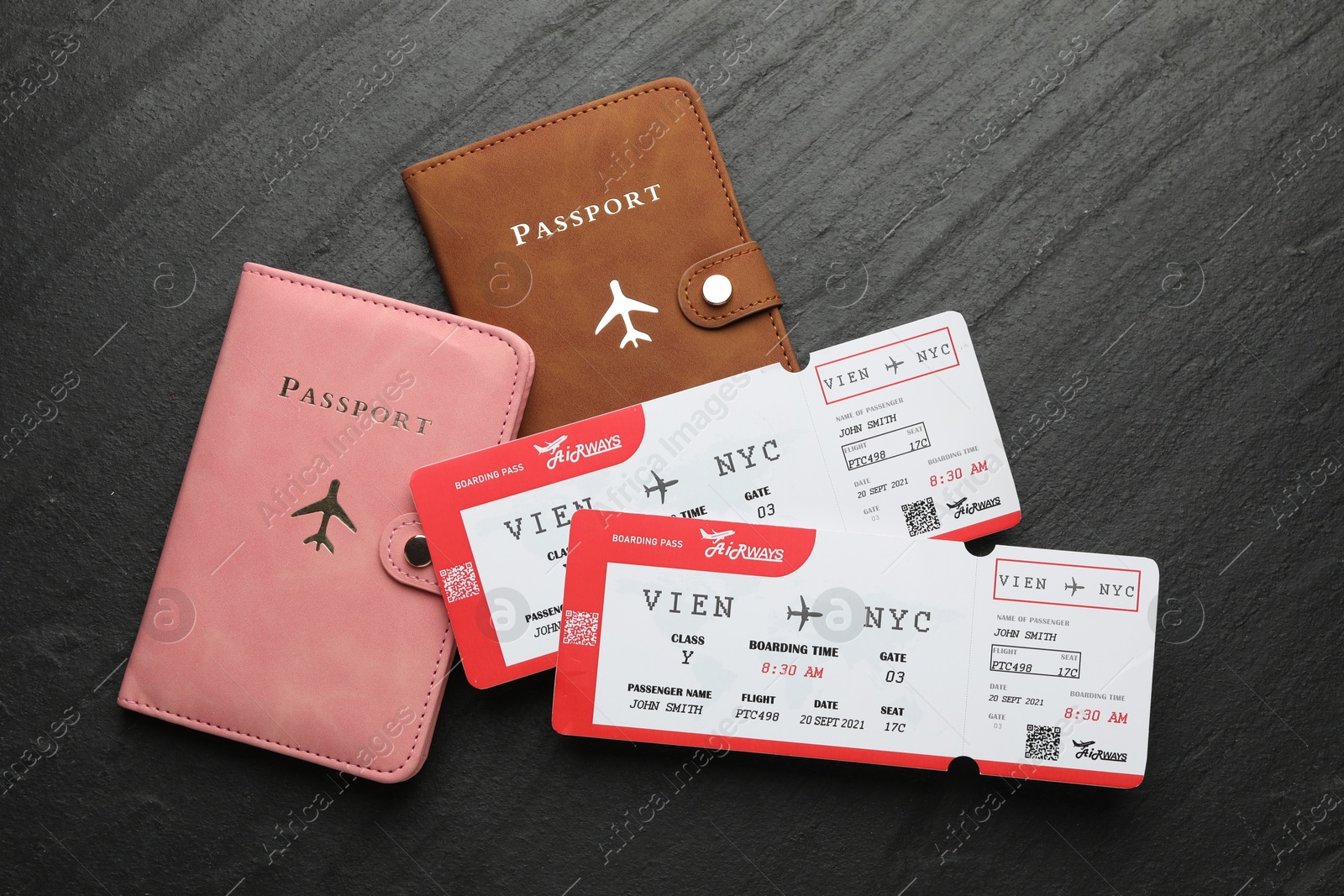 Photo of Travel agency. Flight tickets and passports on dark textured table, flat lay