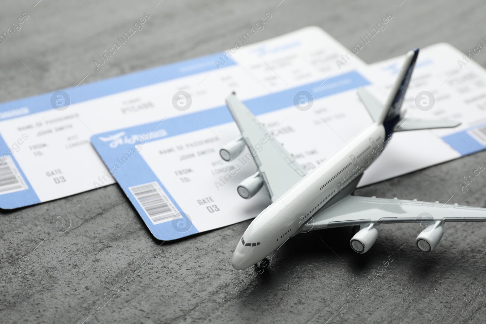 Photo of Travel agency. Flight tickets and plane model on dark textured table, closeup