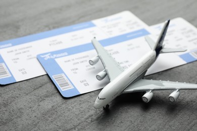 Photo of Travel agency. Flight tickets and plane model on dark textured table, closeup