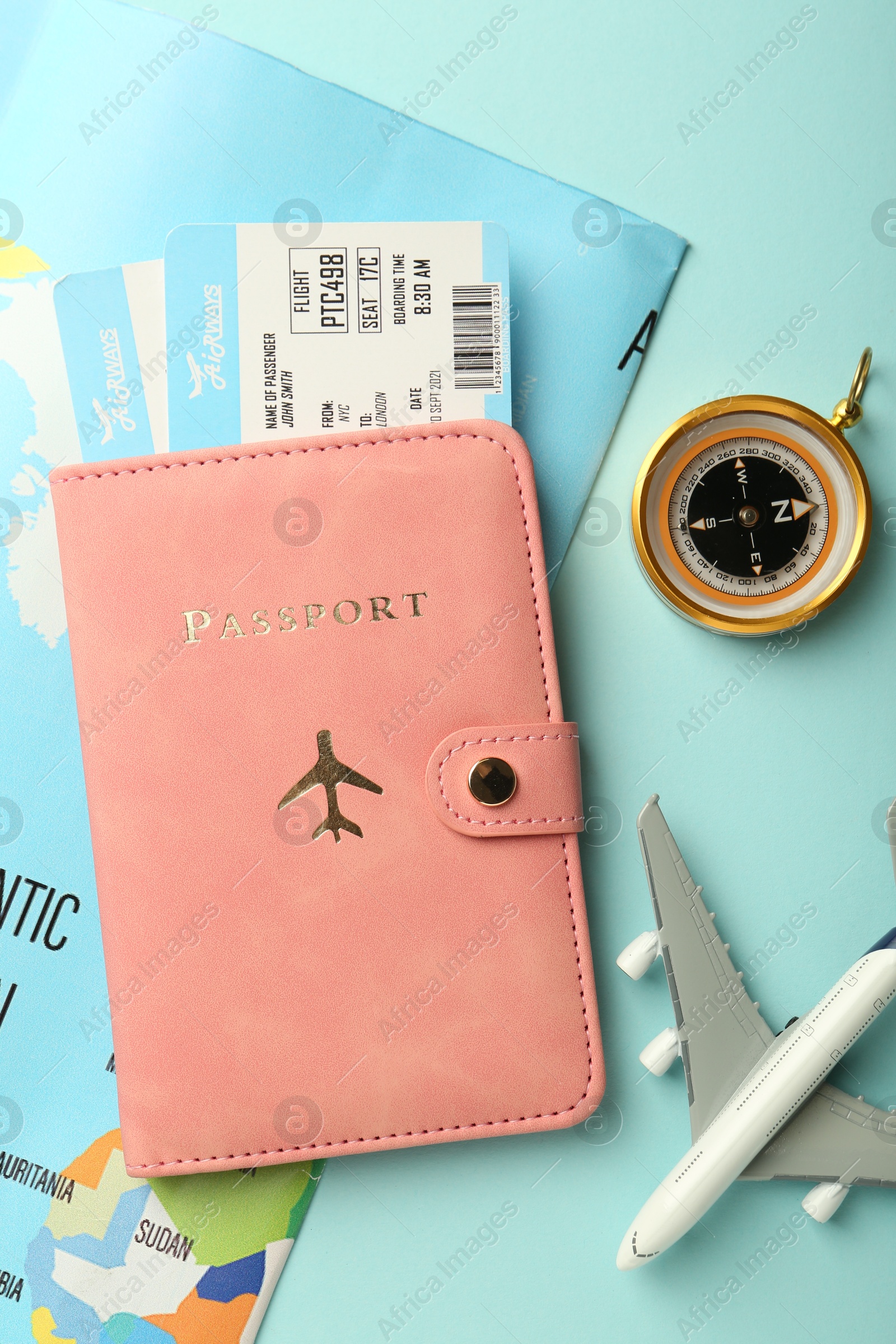 Photo of Passport with tickets, plane model, map and compass on light blue background, flat lay