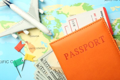 Photo of Passport with tickets, money and plane model on world map, flat lay