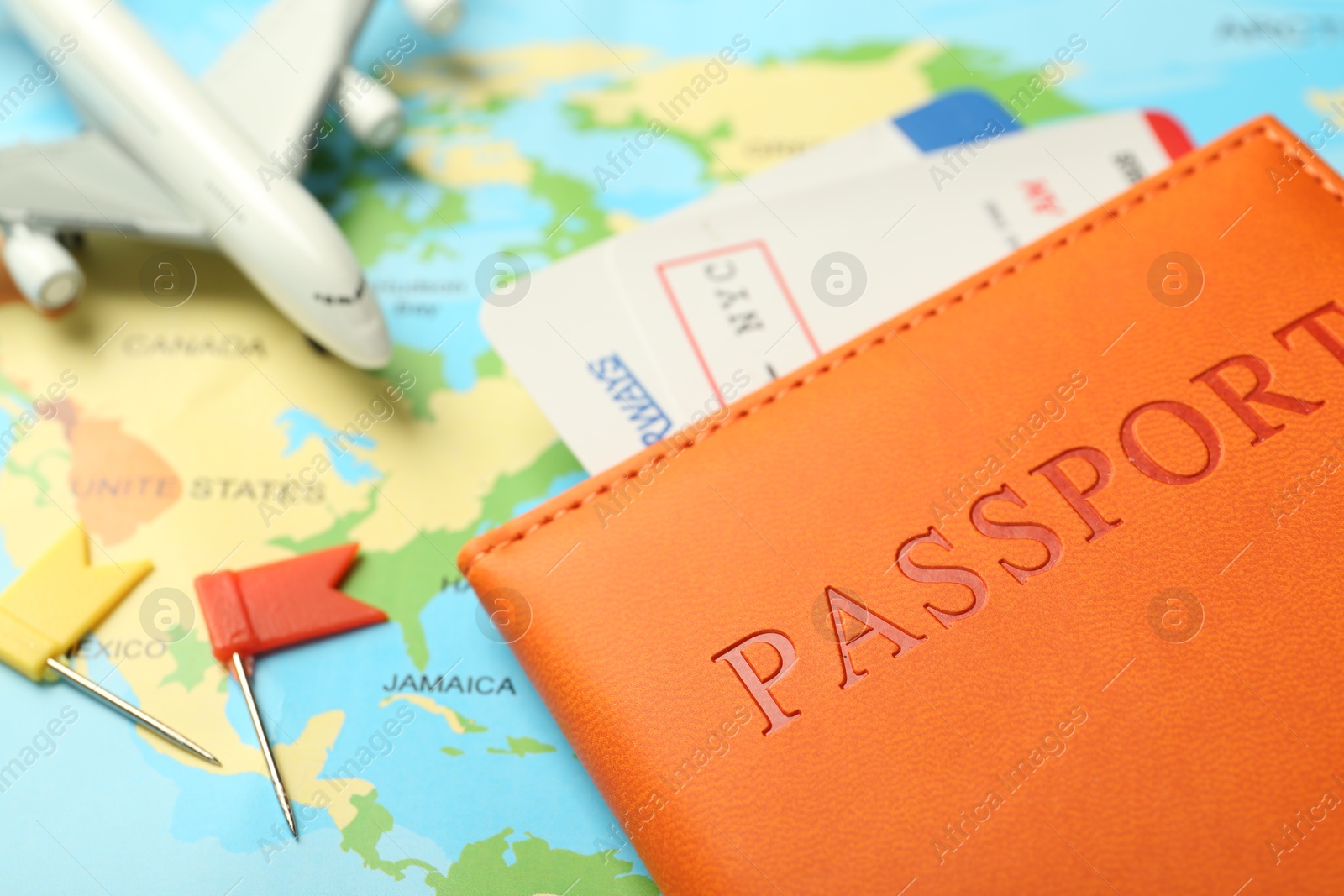 Photo of Passport with tickets and plane model on world map, closeup