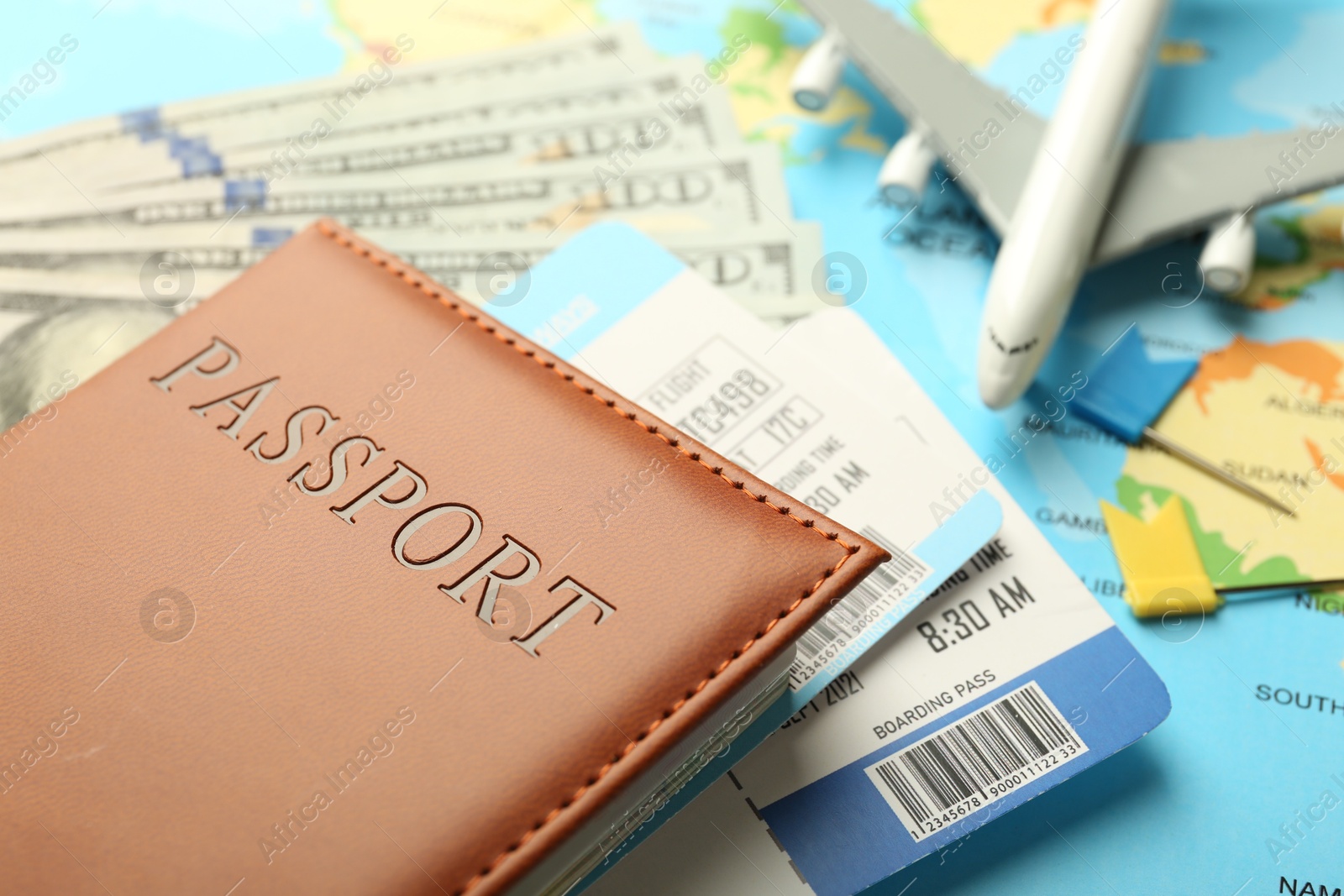 Photo of Passport with tickets, money and plane model on world map, closeup