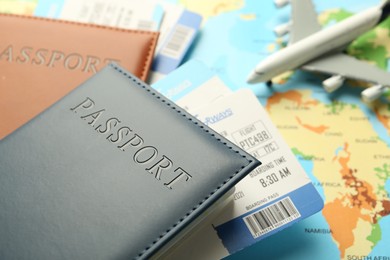 Photo of Passports with tickets and plane model on world map, closeup