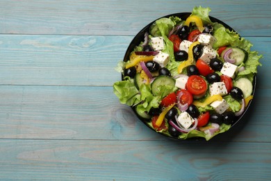 Photo of Delicious fresh Greek salad on light blue wooden table, top view. Space for text