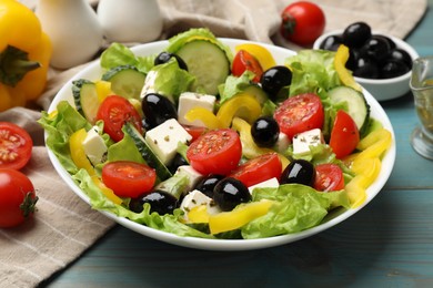 Photo of Delicious fresh Greek salad and ingredients on light blue wooden table, closeup