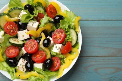 Photo of Delicious fresh Greek salad on light blue wooden table, top view. Space for text