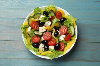 Photo of Delicious fresh Greek salad on light blue wooden table, top view