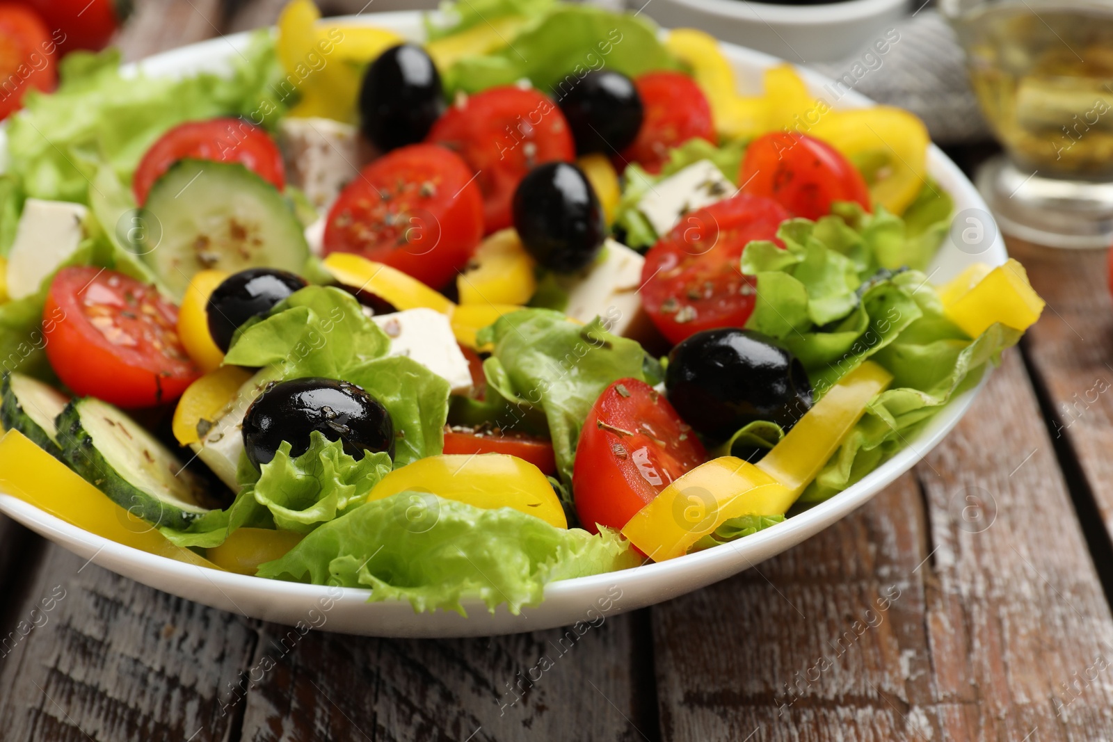 Photo of Delicious fresh Greek salad on wooden table, closeup