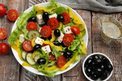 Photo of Delicious fresh Greek salad and ingredients on wooden table, flat lay