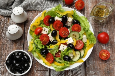 Photo of Delicious fresh Greek salad and ingredients on wooden table, flat lay