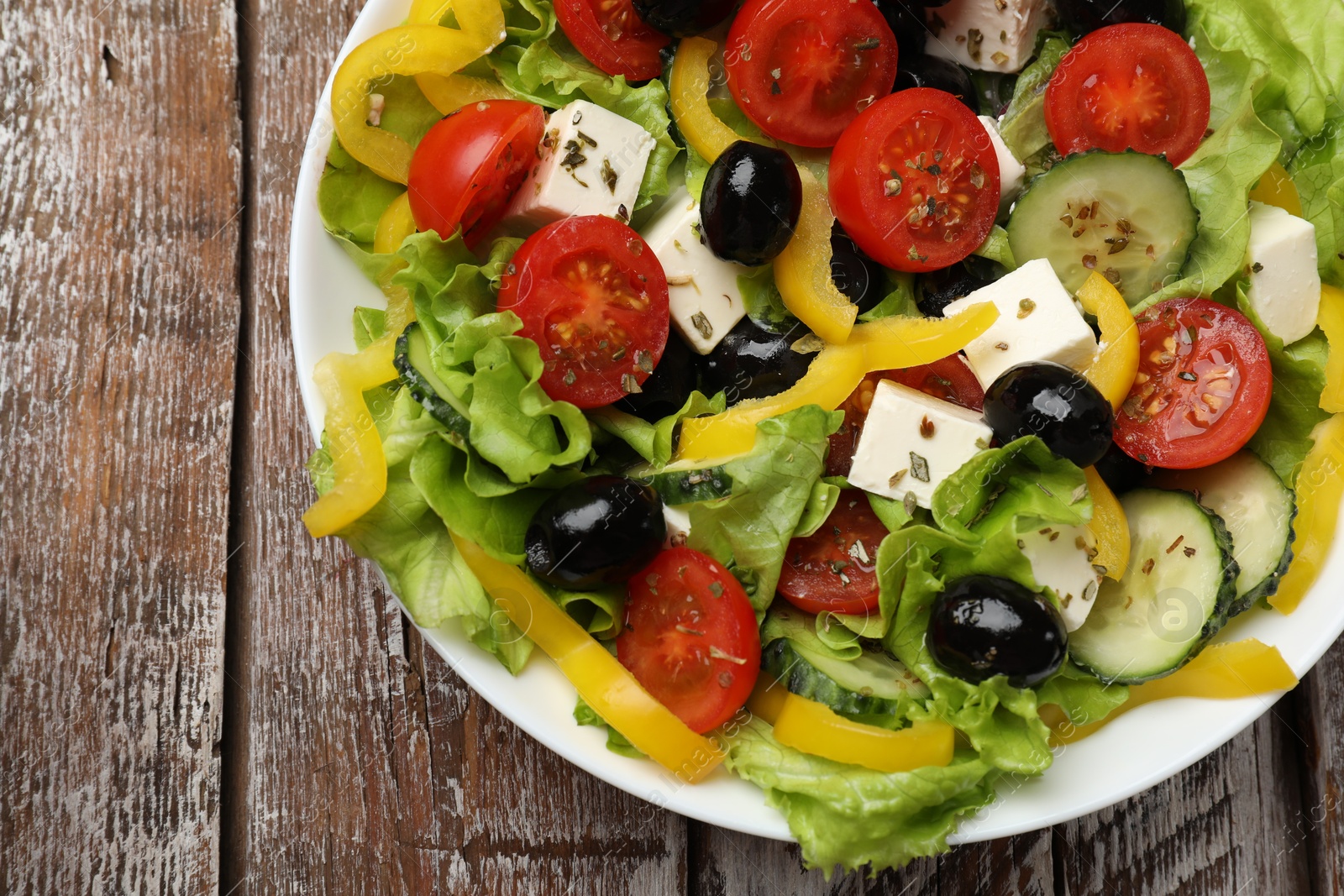 Photo of Delicious fresh Greek salad on wooden table, top view