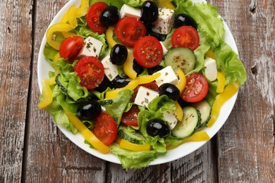 Photo of Delicious fresh Greek salad on wooden table, top view