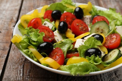 Photo of Delicious fresh Greek salad on wooden table, closeup