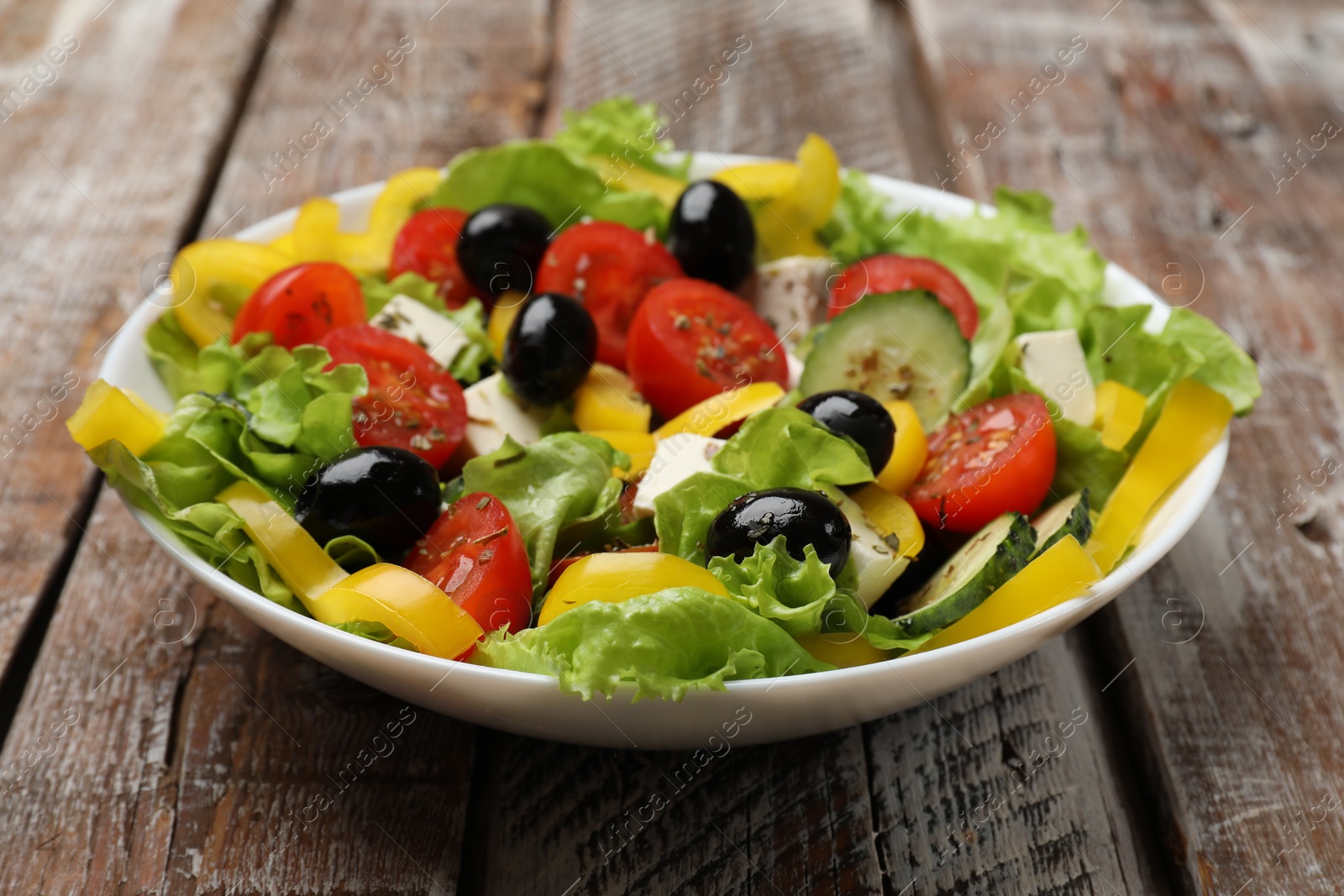 Photo of Delicious fresh Greek salad on wooden table, closeup