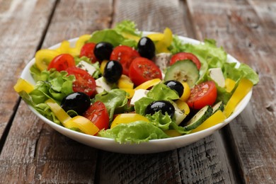 Photo of Delicious fresh Greek salad on wooden table, closeup