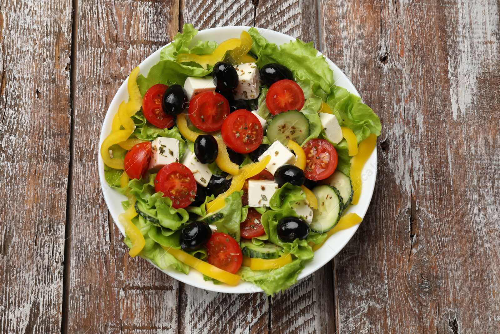 Photo of Delicious fresh Greek salad on wooden table, top view