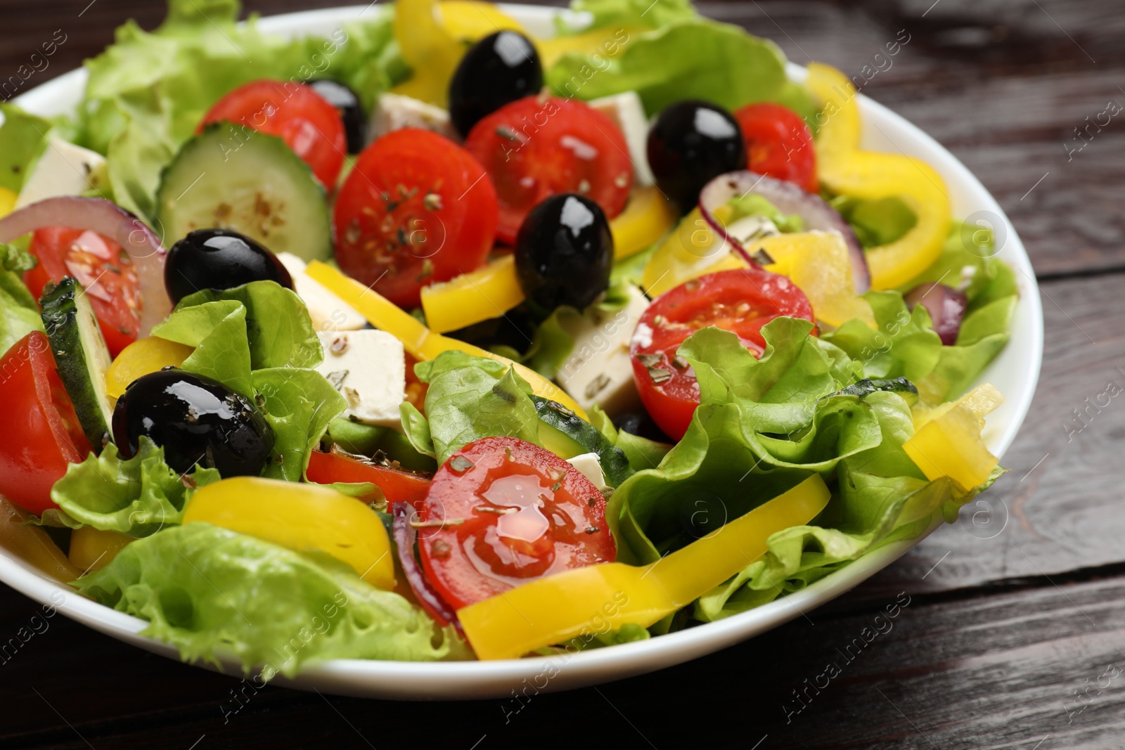 Photo of Delicious fresh Greek salad on wooden table, closeup