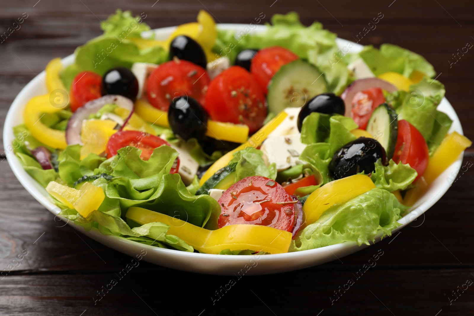 Photo of Delicious fresh Greek salad on wooden table, closeup