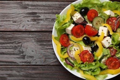 Photo of Delicious fresh Greek salad on wooden table, top view. Space for text